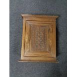 An antique oak wall cabinet with a carved panel door.