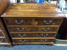 An inlaid yew wood five drawer chest on bracket feet.