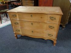 A blonde oak serpentine fronted three drawer chest. Height 69 cm, width 97 cm, depth 47 cm.