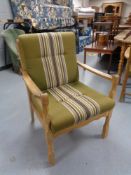 A blond oak framed armchair in green striped fabric