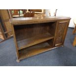 A set of twentieth century oak open bookshelves with carved panel door on bun feet (as found)