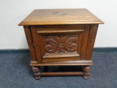 An early 20th century carved oak panel door cabinet on raised legs.