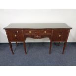 A Regency style mahogany serpentine fronted sideboard on raised legs with glass top.