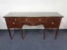 A Regency style mahogany serpentine fronted sideboard on raised legs with glass top.