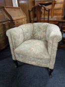 A 20th century tub chair upholstered in a floral fabric on Queen Anne legs.