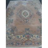 A large Chinese floral embossed fringed carpet on pink ground,