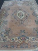 A large Chinese floral embossed fringed carpet on pink ground,