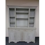 A shabby chic bookcase, fitted cupboards and drawers beneath.