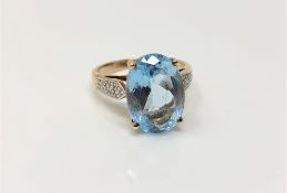 A 9ct gold ring set with an oval blue stone, size N, with diamond set shoulders, 4.7g.