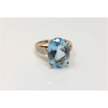 A 9ct gold ring set with an oval blue stone, size N, with diamond set shoulders, 4.7g.