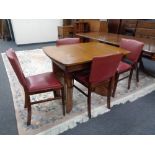 A mid 20th century walnut extending dining table together with a set of four chairs.