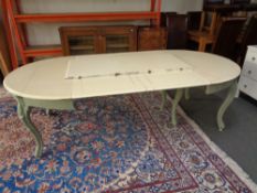 A painted circular continental dining table with three extension leaves