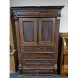 An antique stained pine storage cupboard in the form of a chest.