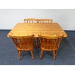 A contemporary pine kitchen table together with a set of four spindle back chairs.