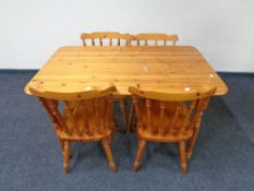 A contemporary pine kitchen table together with a set of four spindle back chairs.