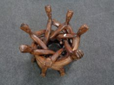 A folding stained beech table base modelled as seven figures.