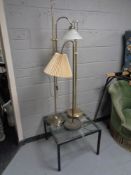 A glass topped coffee table on metal base together with three brass angle poise and standard floor