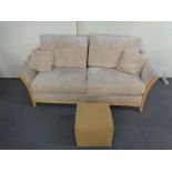 A wooden framed two seater settee in beige fabric together with a foot cube