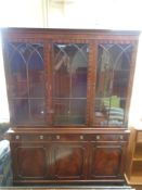 A reproduction Regency style triple door bookcase fitted cupboards and drawers with lion mask