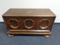 An early 20th century oak three door low sideboard with walnut panel doors.