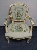 A cream and gilt French salon armchair upholstered in a tapestry fabric.