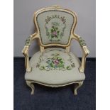 A cream and gilt French salon armchair upholstered in a tapestry fabric.