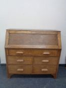 An Edwardian oak writing bureau fitted five drawers beneath.