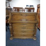 A 20th century oak writing bureau, fitted four drawers below with carved column support on bun feet.