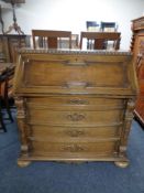 A 20th century oak writing bureau, fitted four drawers below with carved column support on bun feet.