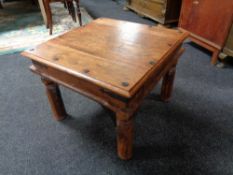 A square hardwood coffee table with metal mounts.