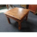 A square hardwood coffee table with metal mounts.