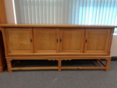 A blond oak four door sideboard on raised legs