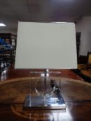 A contemporary table lamp with shade on chrome base