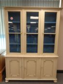 An antique painted pine triple door bookcase with cupboards below,