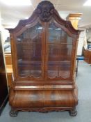 A mahogany bombe double door display cabinet fitted with six drawers on paw feet,