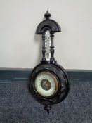 A carved antique ebonised cased barometer with brass enamel dial