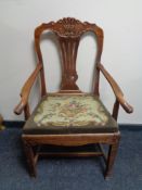 An antique oak armchair with tapestry upholstered seat.