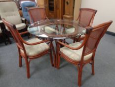 A bamboo and wicker circular glass topped conservatory table and four chairs