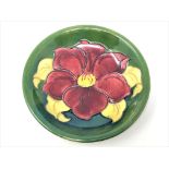 A Walter Moorcroft 'Clematis' pattern plate on green ground, Queen Mary Label, diameter 18.5cm.