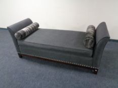 A contemporary chaise longue upholstered in a grey fabric with two bolster cushions