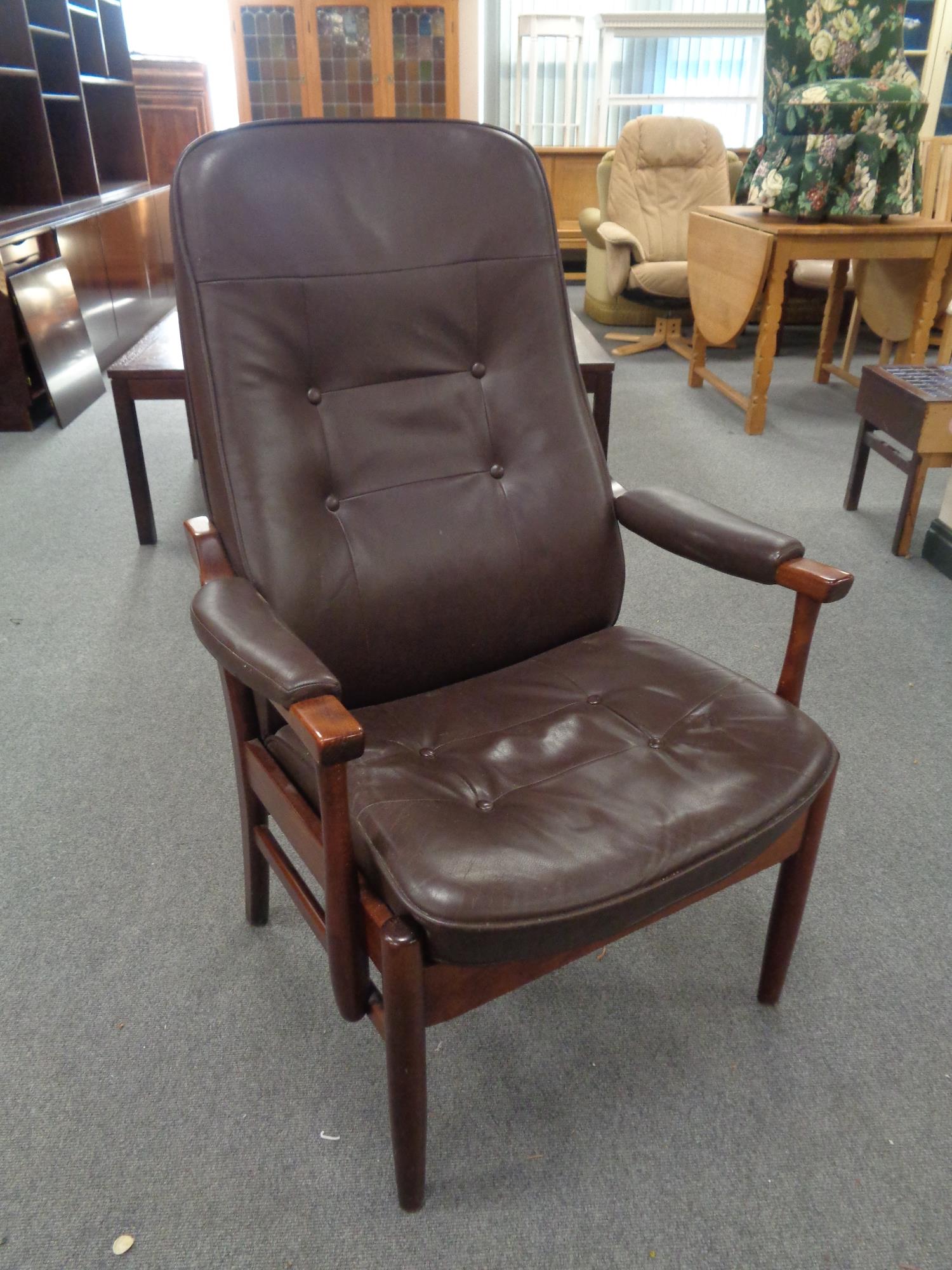 A stained beech framed armchair in brown buttoned leather
