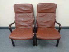 A pair of stained beech framed armchairs with brown leather cushions