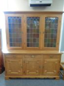 A blond oak stained leaded glass triple door dresser,