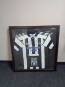 A signed Newcastle United football shirt with accompanying photograph of Steven Taylor in frame.