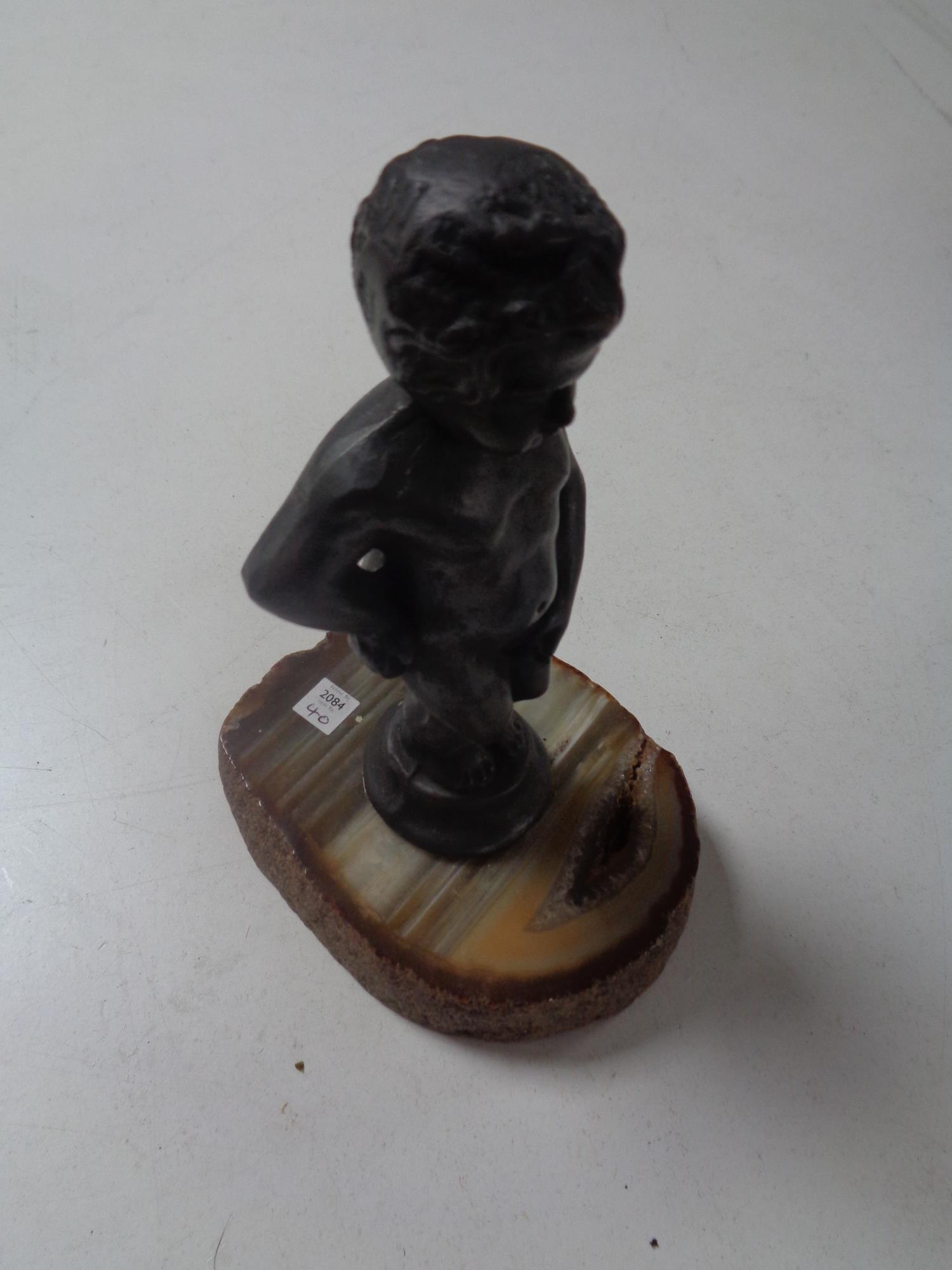 A bronze figure of a boy on polished stone base