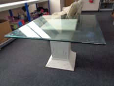 A contemporary glass topped table on pedestal