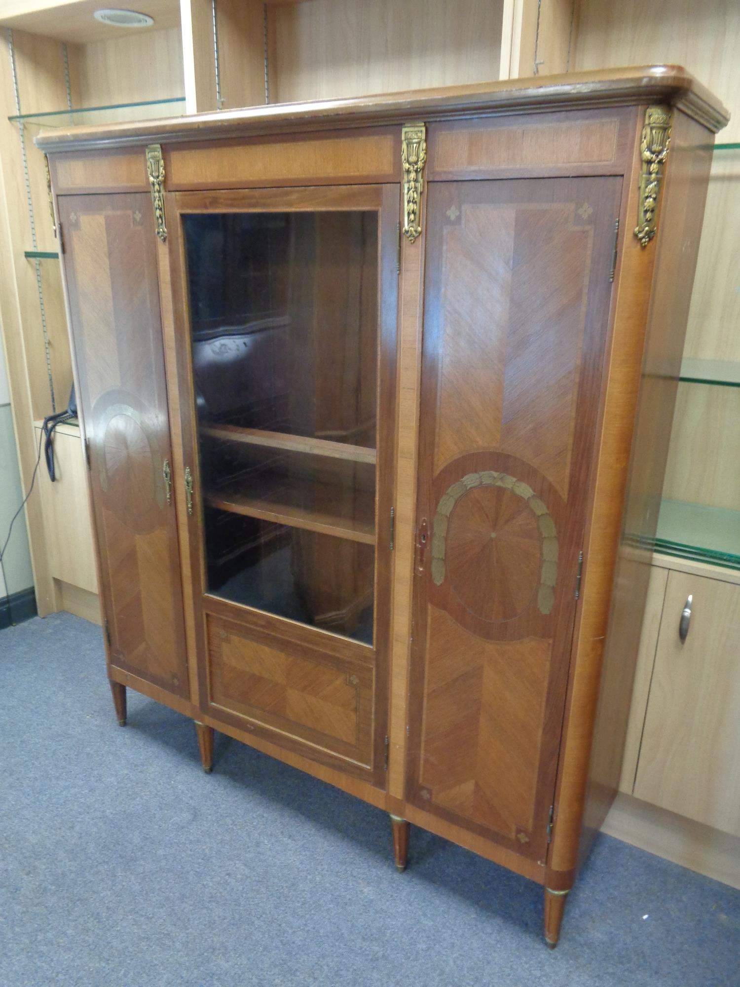 A continental inlaid mahogany triple door cabinet with brass mounts