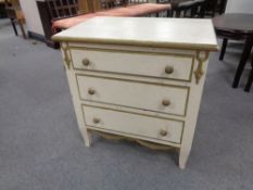 A twentieth century white and gilt painted three drawer chest,