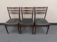 A set of three mid century black leather seated dining chairs