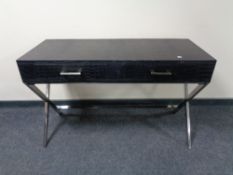 A contemporary black leather two drawer console table on chrome X-frame support.